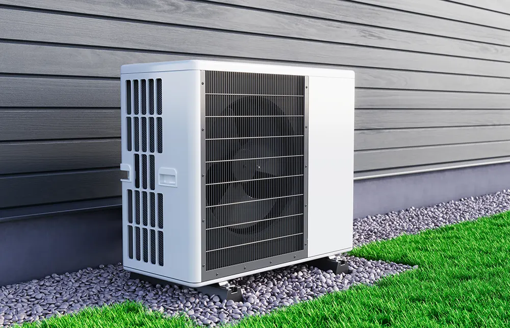 Modern outdoor heat pump unit installed beside a house on a gravel base.