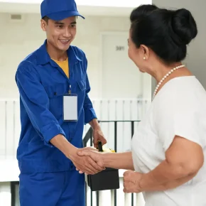 An HVAC technician shaking hands with a woman after completing a repair.